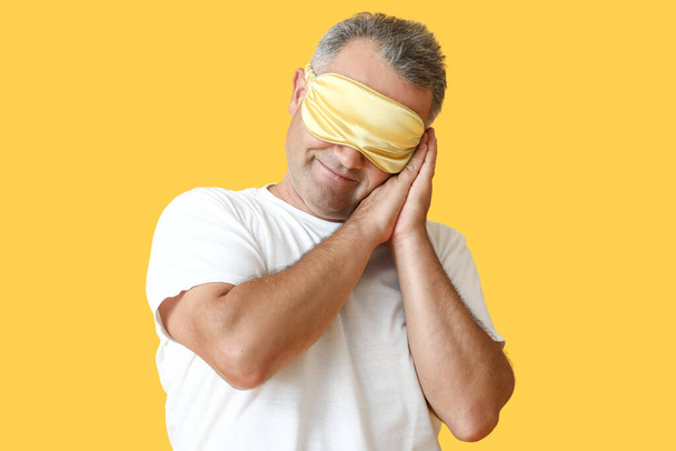 Mature man with sleep mask on color background - Photo, Image