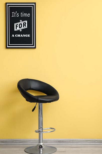 Stylish poster and comfortable chair near yellow wall - Foto, Bild