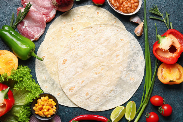 Tortillas and fresh ingredients for preparing tasty burrito on dark background - Photo, Image