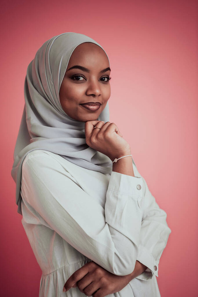 Portrait of young modern muslim afro beauty wearing traditional islamic clothes on plastic pink background. Selective focus  - Foto, imagen