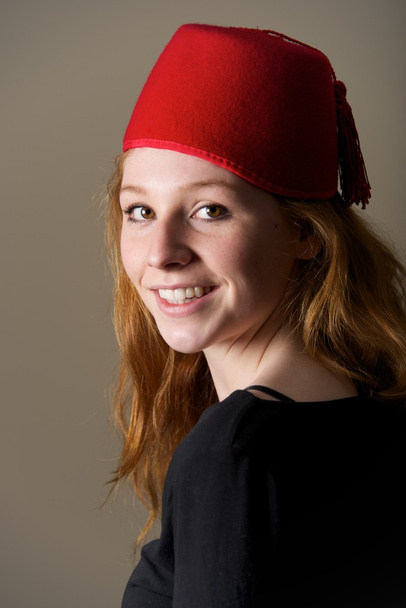 Smiling redhead in fez looking over shoulder - Photo, Image