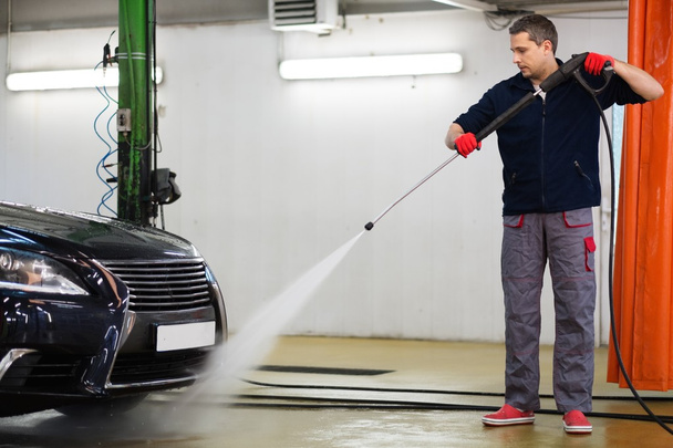 Працівник чоловіка миє розкішний автомобіль на автомийці
  - Фото, зображення