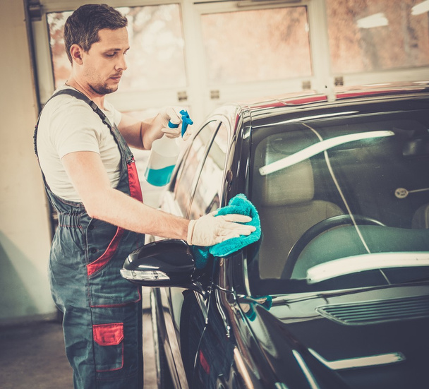 Worker on a car wash cleaning car with a spray - Fotoğraf, Görsel