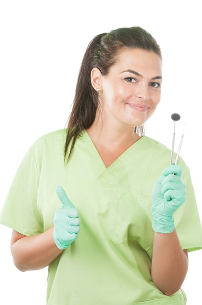 Mulher dentista segurando ferramentas profissionais e mostrando polegares para cima
 - Foto, Imagem