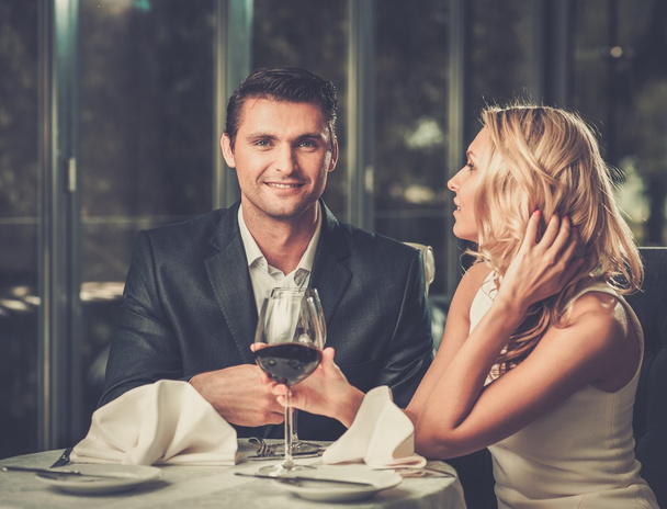 Χαρούμενο ζευγάρι σε ένα εστιατόριο με ποτήρια κόκκινο κρασί - Φωτογραφία, εικόνα