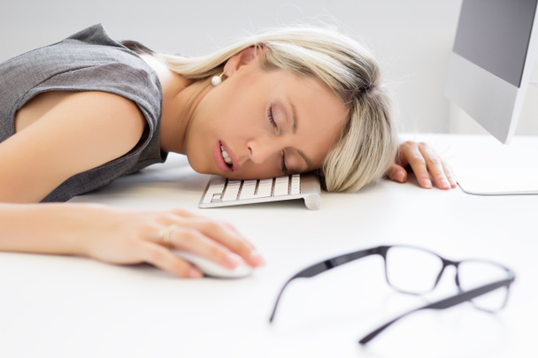Exhausted woman sleeping in front of computer - 写真・画像