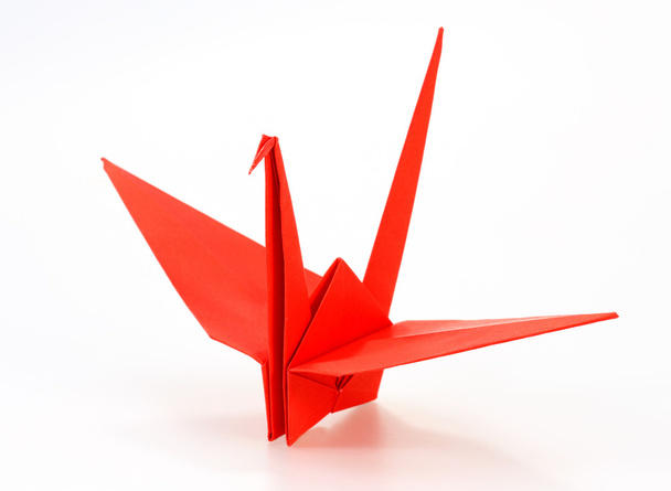 Traditional Japanese origami crane made of red paper over white  - Foto, afbeelding