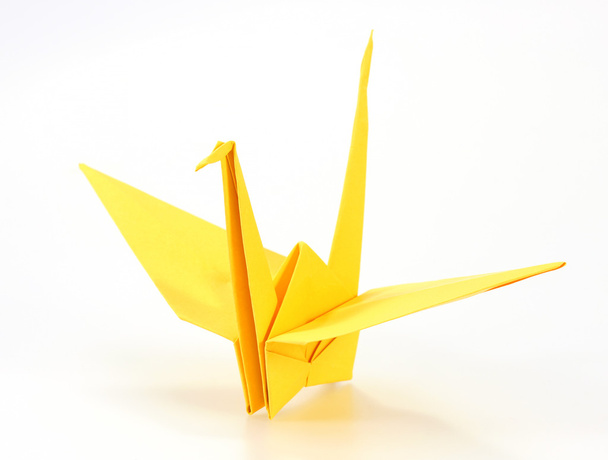Traditional Japanese origami crane made of yellow paper over whi - Foto, immagini
