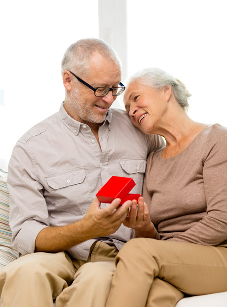 happy senior couple with red gift box at home - Zdjęcie, obraz