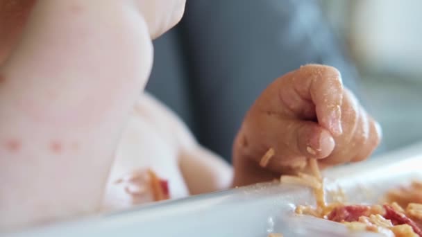 Retrato de cerca de una niña comiendo su cena de espaguetis y haciendo un desastre. Bebé desordenado. Estilo de vida saludable. - Metraje, vídeo