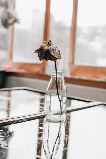 Roses fanées et herbe sèche dans un bocal en verre. Concept de solitude ou d'âge dans le ton vintage. - Photo, image