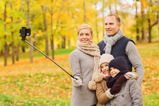 happy family with smartphone and monopod in park - Foto, afbeelding