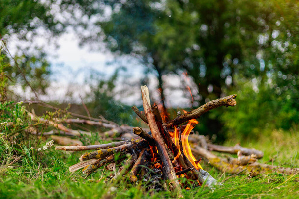 Vuur of kampvuur in de natuur in een toeristenkamp op een kampeertocht. Achtergrond met kopieerruimte voor tekst - Foto, afbeelding