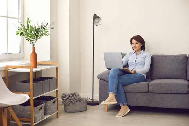 Casual female manager working on laptop sitting on comfortable sofa in modern bright office. - Fotoğraf, Görsel