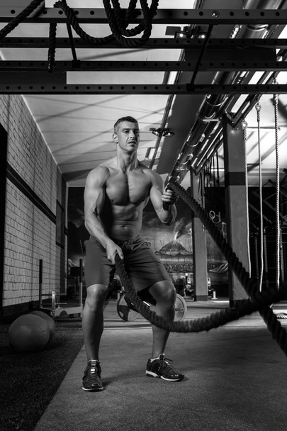 man op gym training oefening vechten touwen - Foto, afbeelding