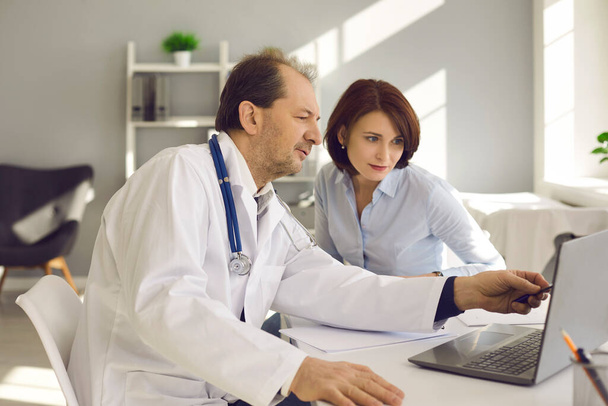 Mujer escuchando al médico y mirando a la pantalla del ordenador portátil con resultados de exámenes de salud - Foto, imagen