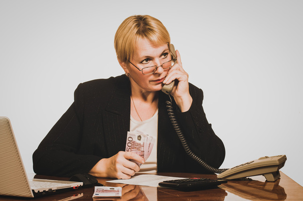 Mature businesswoman waiting for answer on the phone with money  - Фото, изображение
