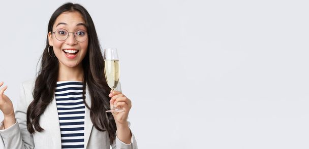 Business, finance and employment, female successful entrepreneurs concept. Enthusiastic happy businesswoman celebrating good deal, have office party with coworkers, make toast with glass champagne - Photo, Image