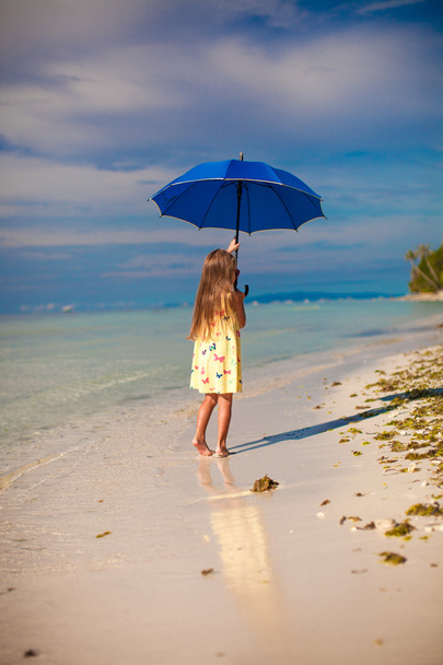 Menina bonito pouco com guarda-chuva azul andando na praia tropical
 - Foto, Imagem