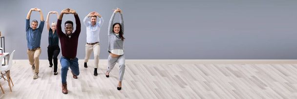 Group Of Happy Young Businesspeople Doing Stretching Exercise In Office - Fotografie, Obrázek