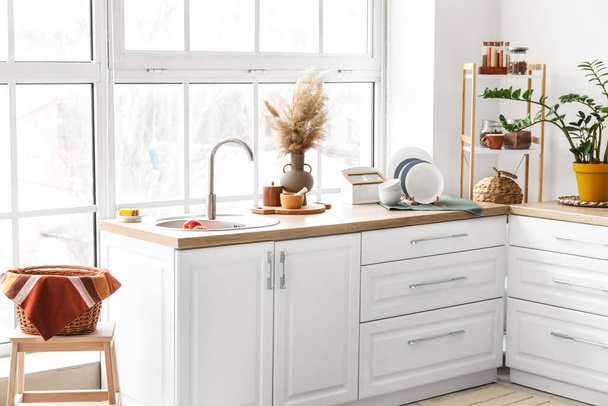 Holztische mit Spüle und verschiedenen Kochutensilien in heller Küche - Foto, Bild