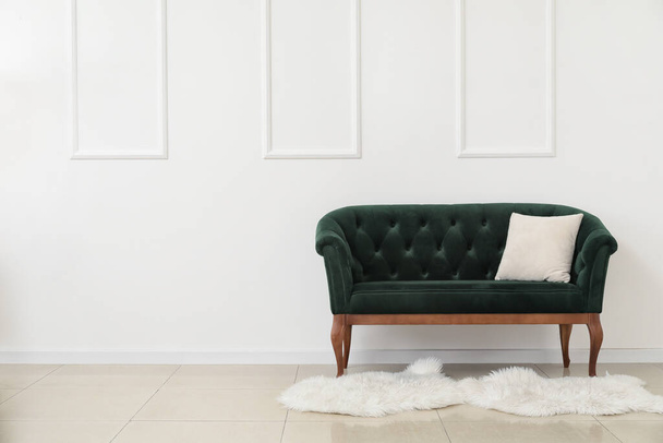 Νέος πράσινος καναπές με μαξιλάρι κοντά σε λευκό τοίχο - Φωτογραφία, εικόνα