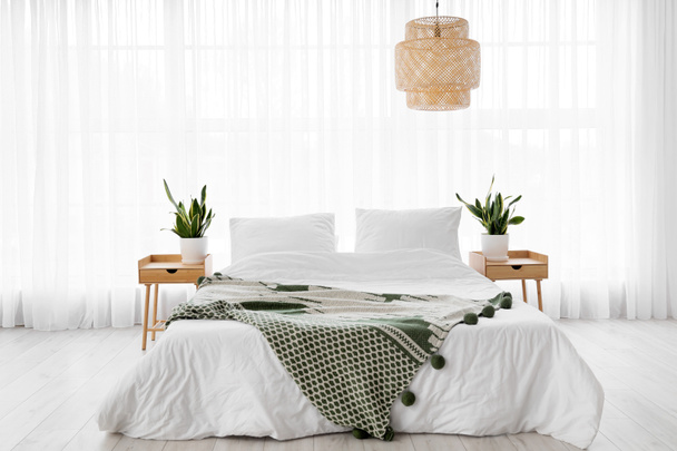 快適なベッド、ナイトスタンド、客室内の観葉植物 - 写真・画像