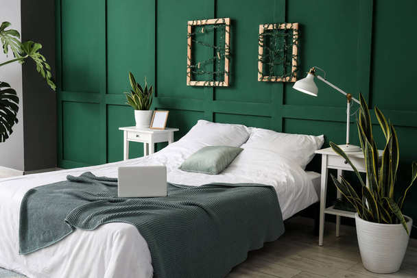 Wnętrze stylowej sypialni z roślinami w pobliżu zielonej ściany - Zdjęcie, obraz