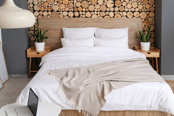 Удобная кровать и тумбочки возле деревянной стены - Фото, изображение