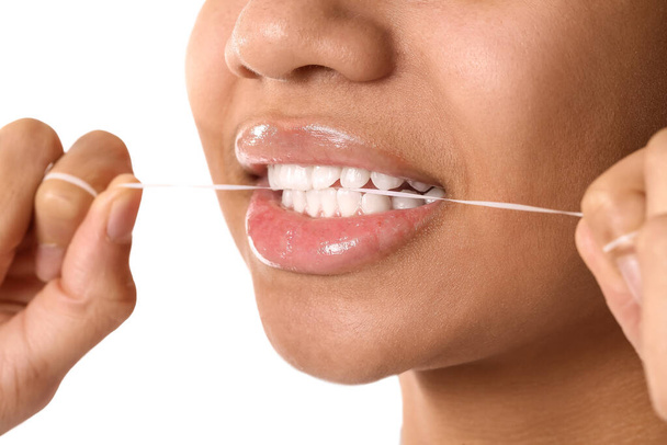 Adolescente afroamericana que usa hilo dental sobre fondo blanco, primer plano - Foto, Imagen