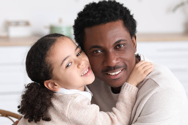 Feliz hombre afroamericano y su pequeña hija abrazándose en casa - Foto, Imagen