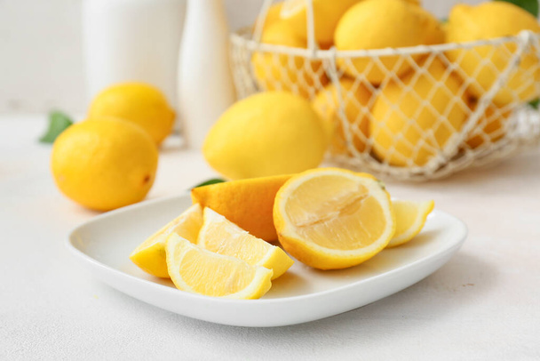 Teller mit frisch geschnittener Zitrone auf hellem Tisch - Foto, Bild