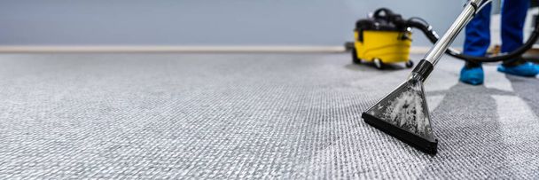 Photo Of Janitor Cleaning Carpet With Vacuum Cleaner - Фото, изображение