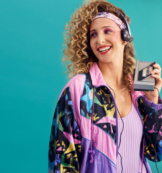 Ничто не заставляет меня чувствовать себя так хорошо, как музыка 80-х. Студийный снимок молодой женщины, держащей кассетный плеер в одежде 80-х годов. - Фото, изображение