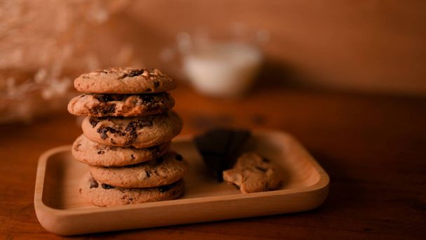 Uma pilha de biscoitos de chocolate ou manteiga de amendoim com pedaços de chocolate biscoitos em um prato de madeira. - Foto, Imagem