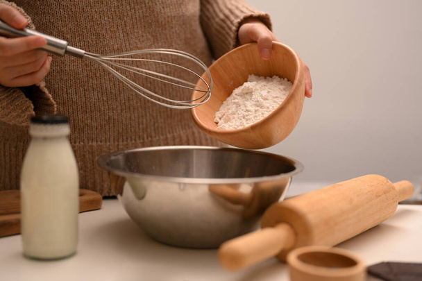 Close-up-Bild, Weibchen, die eine hausgemachte Erdnussbutter-Kekse, gießt eine Tasse Mehl in eine Rührschüssel. Konzept für süßes Gebäck - Foto, Bild