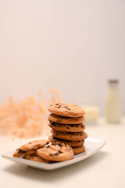 Вкусное шоколадное печенье на белой тарелке на ярком фоне. Печенье с арахисовым маслом и кусочками шоколада. - Фото, изображение