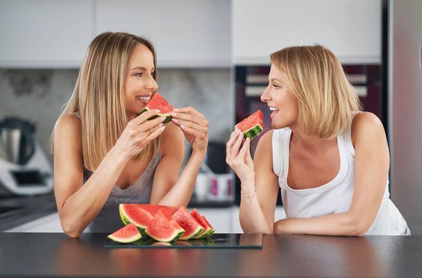 Nice two adult girls in the kitchen with watermelon - Φωτογραφία, εικόνα