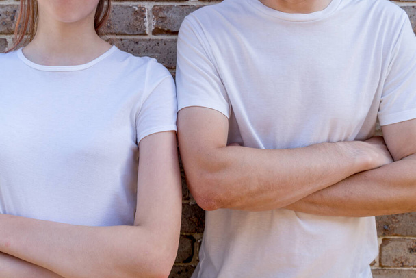 Couple wearing mockup white t-shirts on brick wall background holding hands. Template copy space fashion - Photo, Image