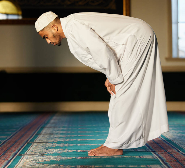 Is prayer your steering wheel or your spare tire. Shot of a young muslim male praying in a mosque. - Photo, image