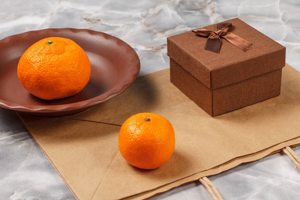 Pomarańcze i pudełko prezentów na kamiennym stole kuchennym. Owoce ekologiczne. - Zdjęcie, obraz