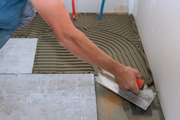 Человек делает с помощью клея цементной базы керамической плитки - Фото, изображение