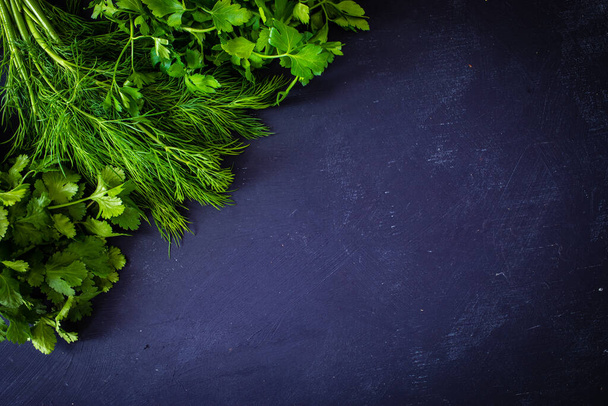 Bunch of parsley, dill and coriander on black table - Фото, изображение