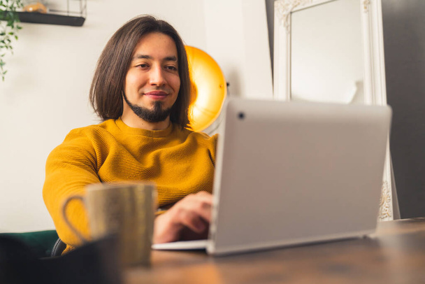 Young European man with straight dark hair and beard works from home in casual attire remote job concept copy space  - Photo, Image