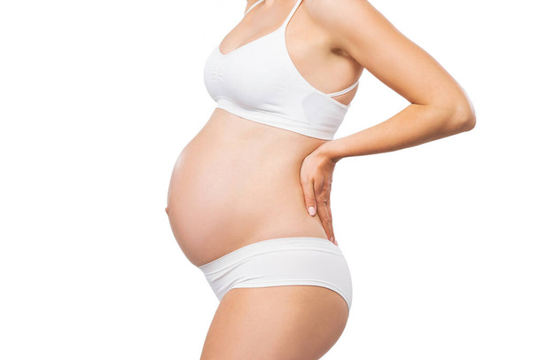 Young pregnant woman in swimsuit. Girl expecting a baby and touching her belly isolated on white background. Close-up image. - Foto, Bild