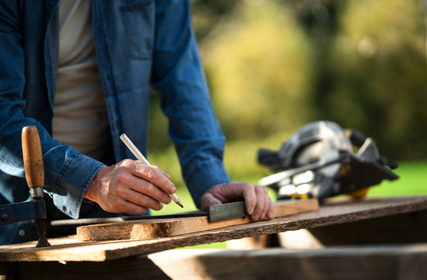 Close-up of handyman measuring a board, outside in garden. - Foto, Imagen