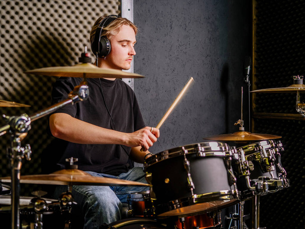 Young man wearing headphones and playing drums in a recording studio. - Photo, Image