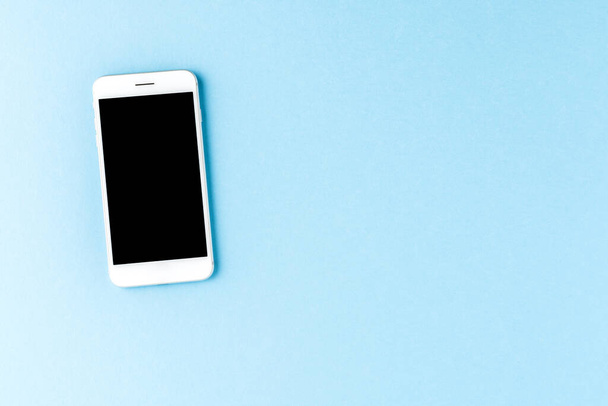 Smart phone with blank screen on blue desktop. Top view - Φωτογραφία, εικόνα