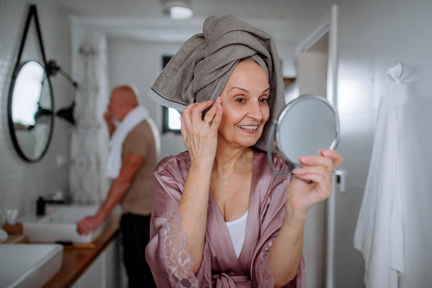 Senior couple in bathroom, brushing teeth and looking at mirror, morning routine concept. - Foto, Bild