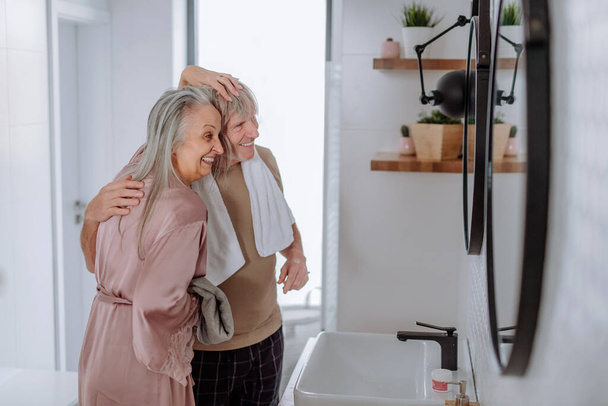 Senior couple in love in bathroom, looking at mirror and having fun, morning routine concept. - Foto, Bild